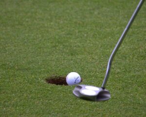 Lähikuva golf-kentästä, mailasta ja pallosta