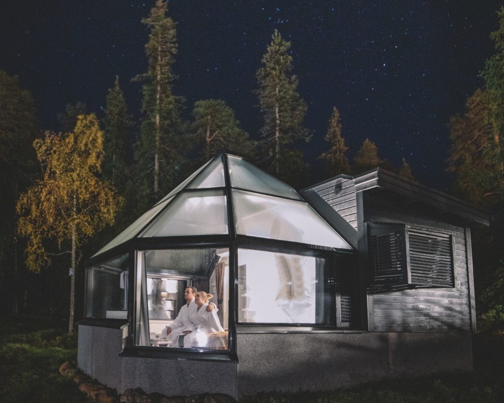 Glass Igloo under a starry sky, with a couple inside looking at the stars