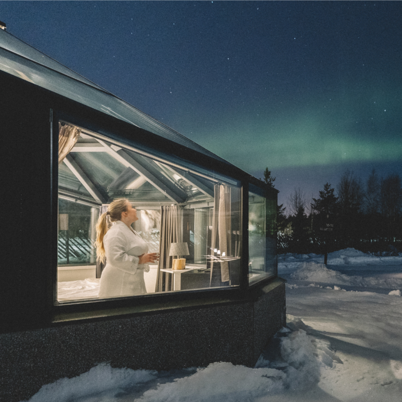 A guest admiring the Aurora Borealis from the inside of her Glass Igloo in Santa's Igloos Arctic Circle