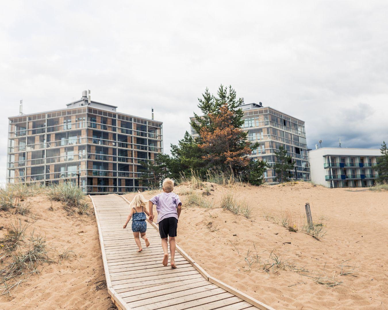 Lapset juoksevat Santa's Resort & Spa Hotel Sanin edustalla olevan hiekkarannan pitkospuilla, jotka ovat leveät ja vaakalaudoitetut ja helpottavat esteetöntä kulkua hiekkarannalla.