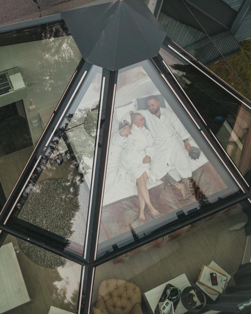 A couple laying in bed inside the glass igloo