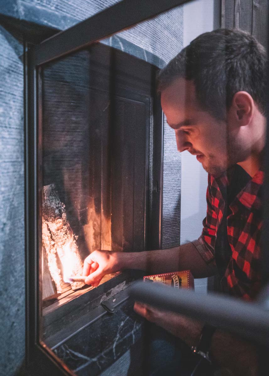 Mies sytyttää takkaa hotellihuoneessa