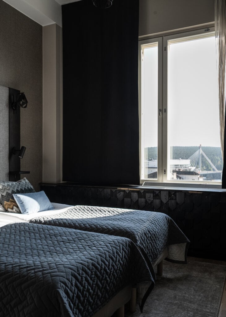 Hotellihuoneen sängyt ja ikkunasta näkyy Jätkänkynttilän silta