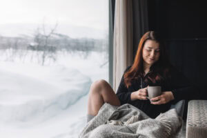 Woman under a blanket with a mug