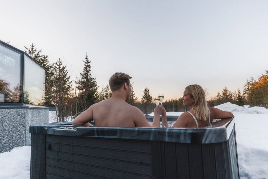 A couple raising a glass in the outdoor jacuzzi in winter