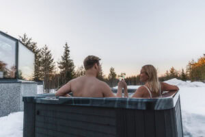 A couple raising a glass in the outdoor jacuzzi in winter
