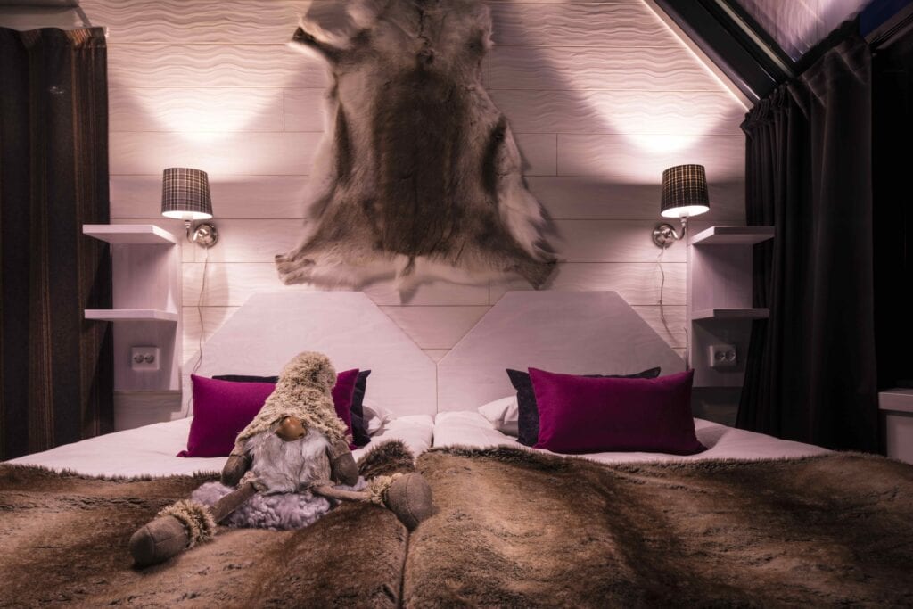 Seppo the Elf sitting on a bed in a glass igloo