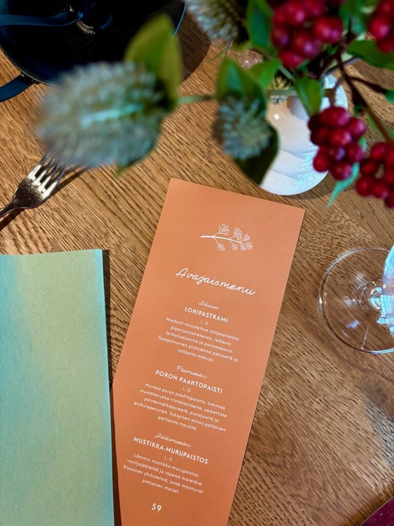 avajaismenu pöydällä kattauksen ja kukkien keskellä