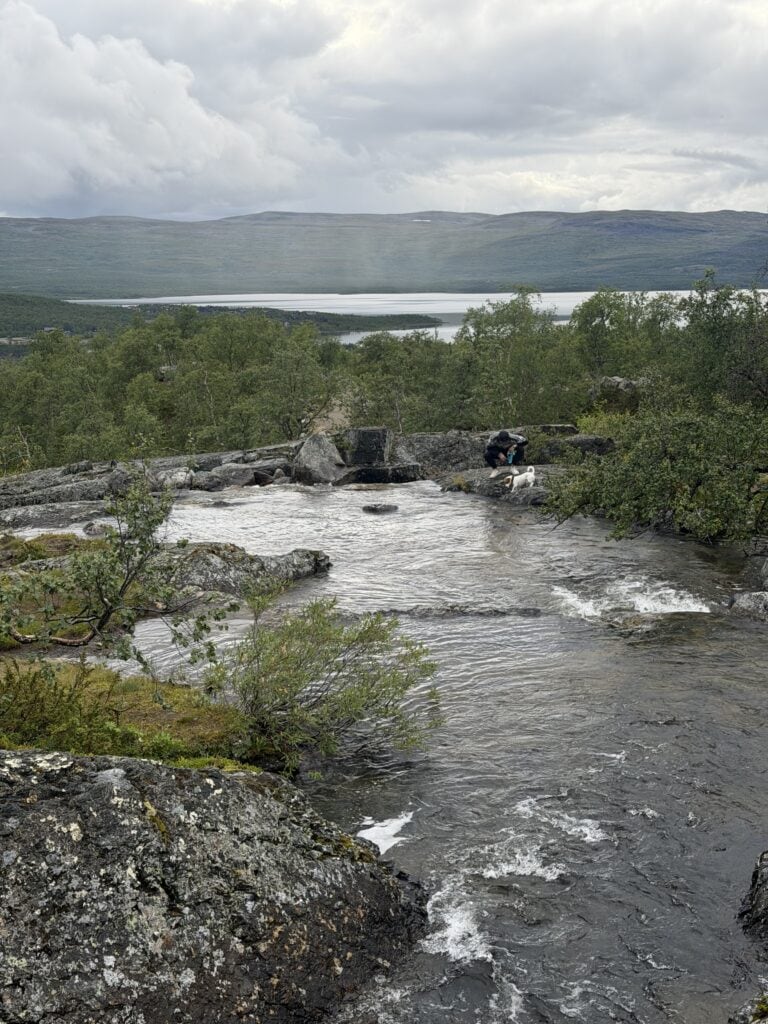 Ihminen ja koira Tsahkalputouksen äärellä Kilpisjärvellä