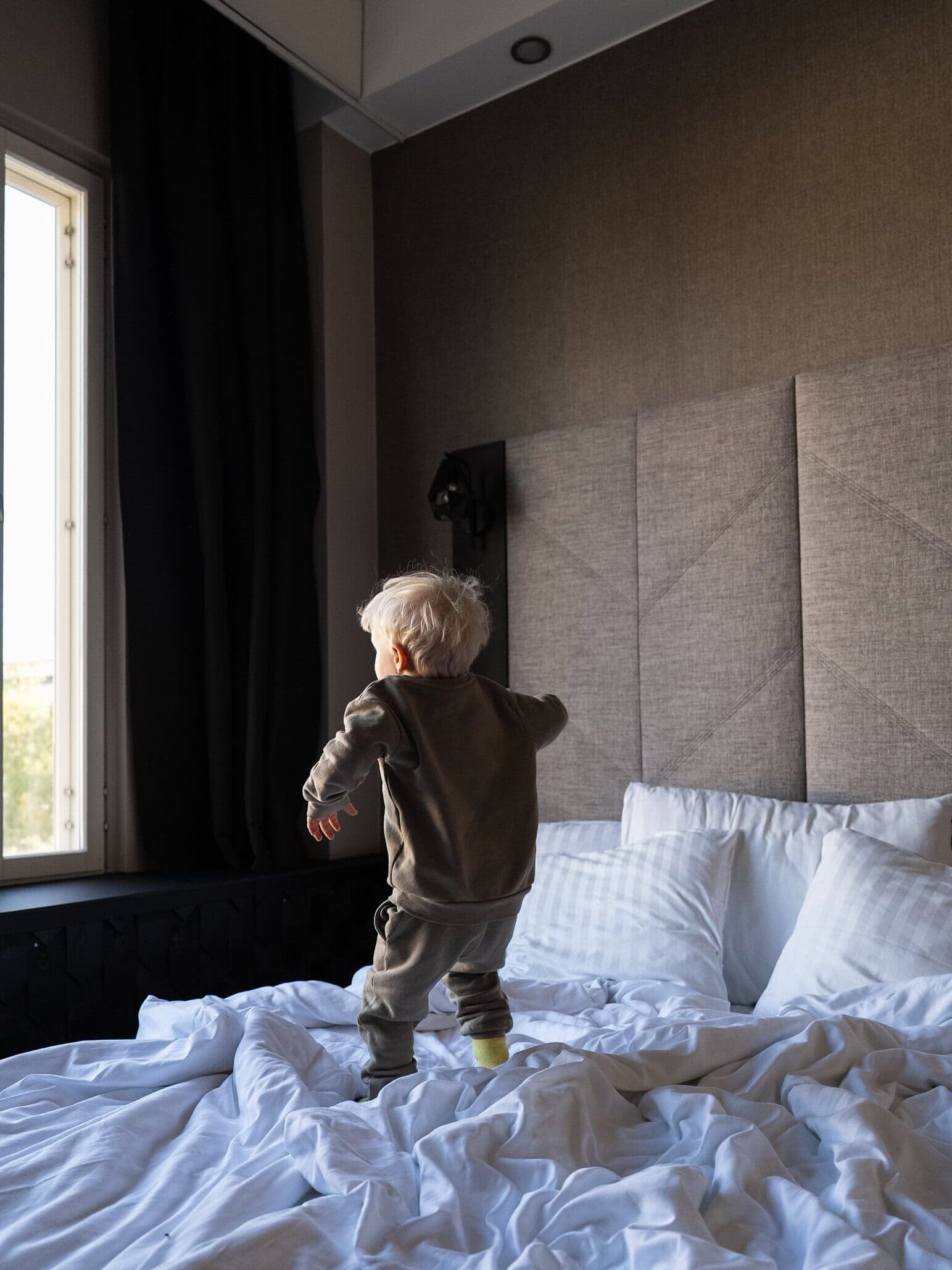 Pieni lapsi hyppii hotellihuoneen sängyllä
